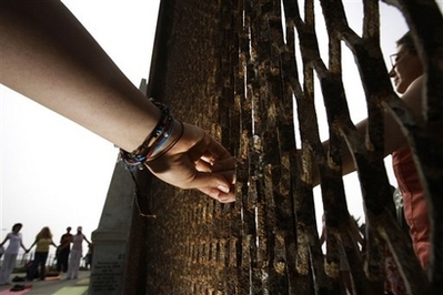 Residents hold hands trough the U.S.-Mexico border fence as they take part in the "Yoga without borders" encounter at the border in Tijuana, Mexico, Sunday, June 22, 2008.(AP Photo/Guillermo Arias)